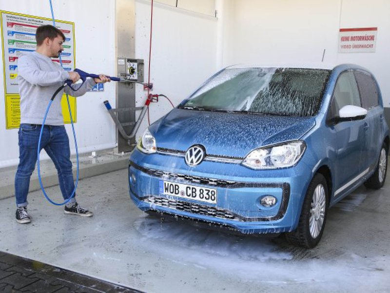 Auto-in-der-Waschanlage.jpg Ein blauer VW UP wird in der Waschanlage von einem Mann geputzt.